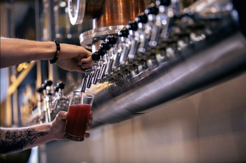 Shot of a person pouring a reddish colored beer from a tap at Ironton Distillery & Crafthouse