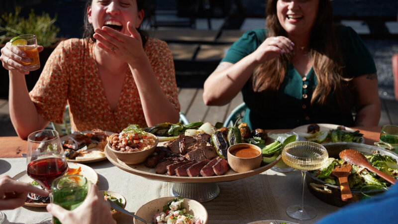 Carriqui - outdoor table with several plated dishes and smiling people