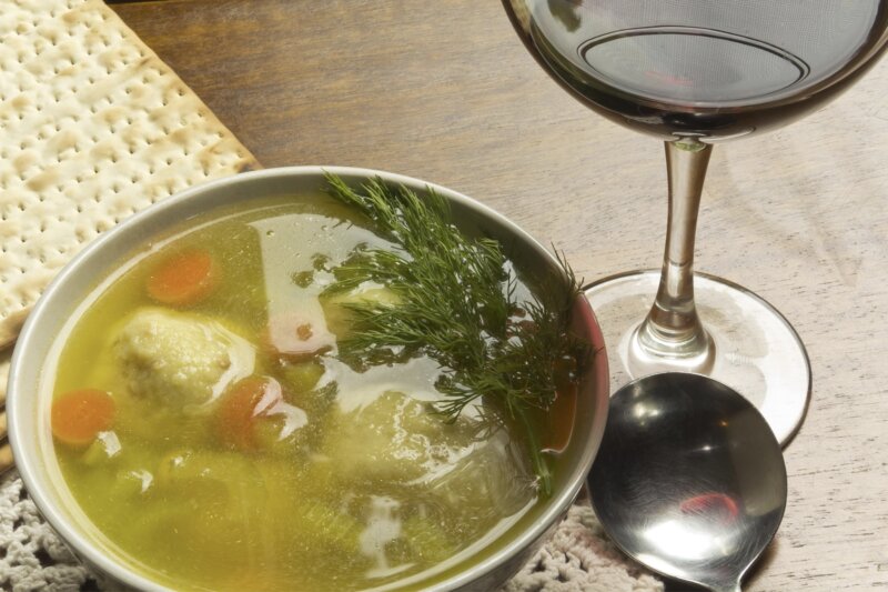 Close up shot of matzo ball soup with a glass of wine