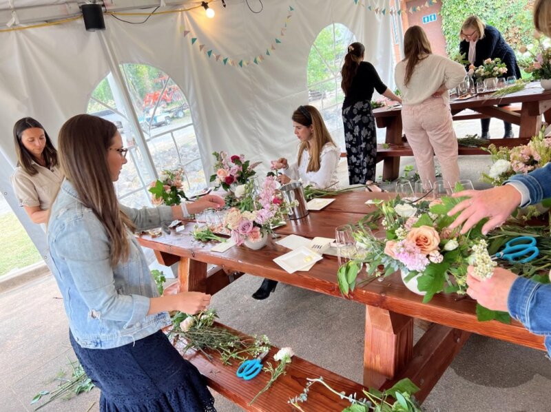 Images of people in a tent putting together flower arrangements