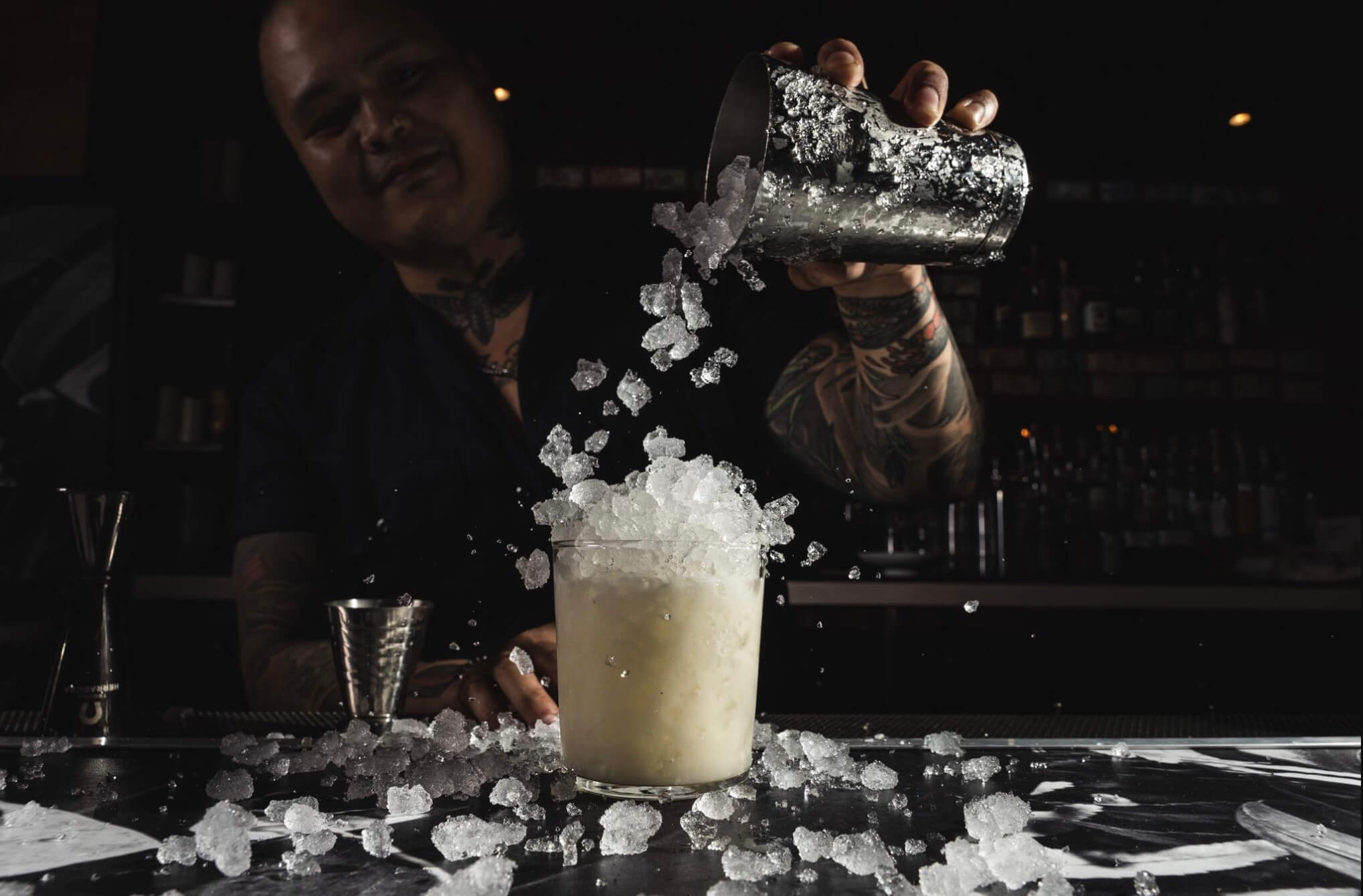 Cover Image for Bartender pouring ice in an overflowing cocktail glass
