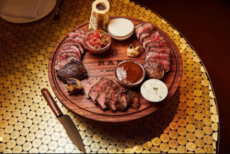Steak, bone marrow, and sauces sitting on a table 