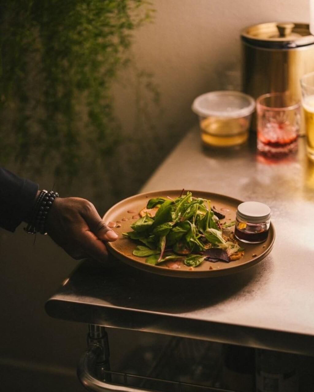 Hand holding a plated dish on the corner of a stainless steel surface