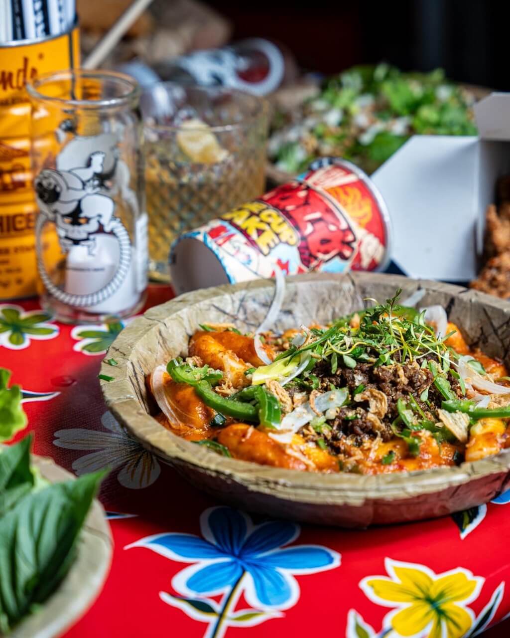 Plated dish on bright, colorful tablecloth with packaged foods and drinks in the background
