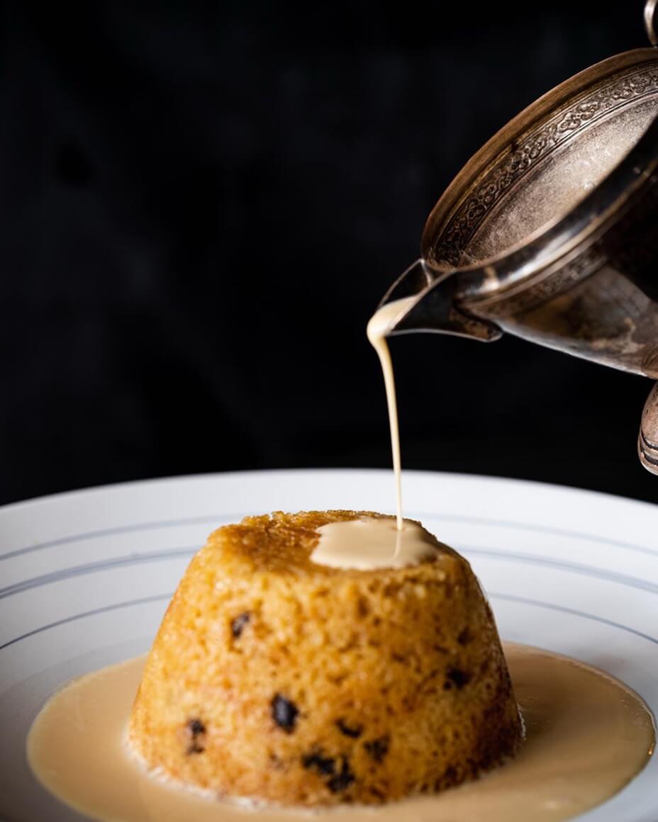 Spotted Dick dessert with Galangal Custard being poured on top