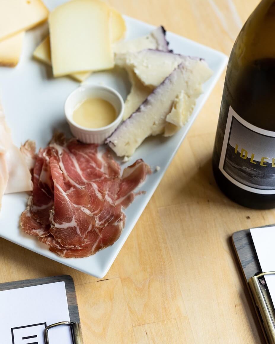 Charcuterie plate next to bottle of Idlewild wine