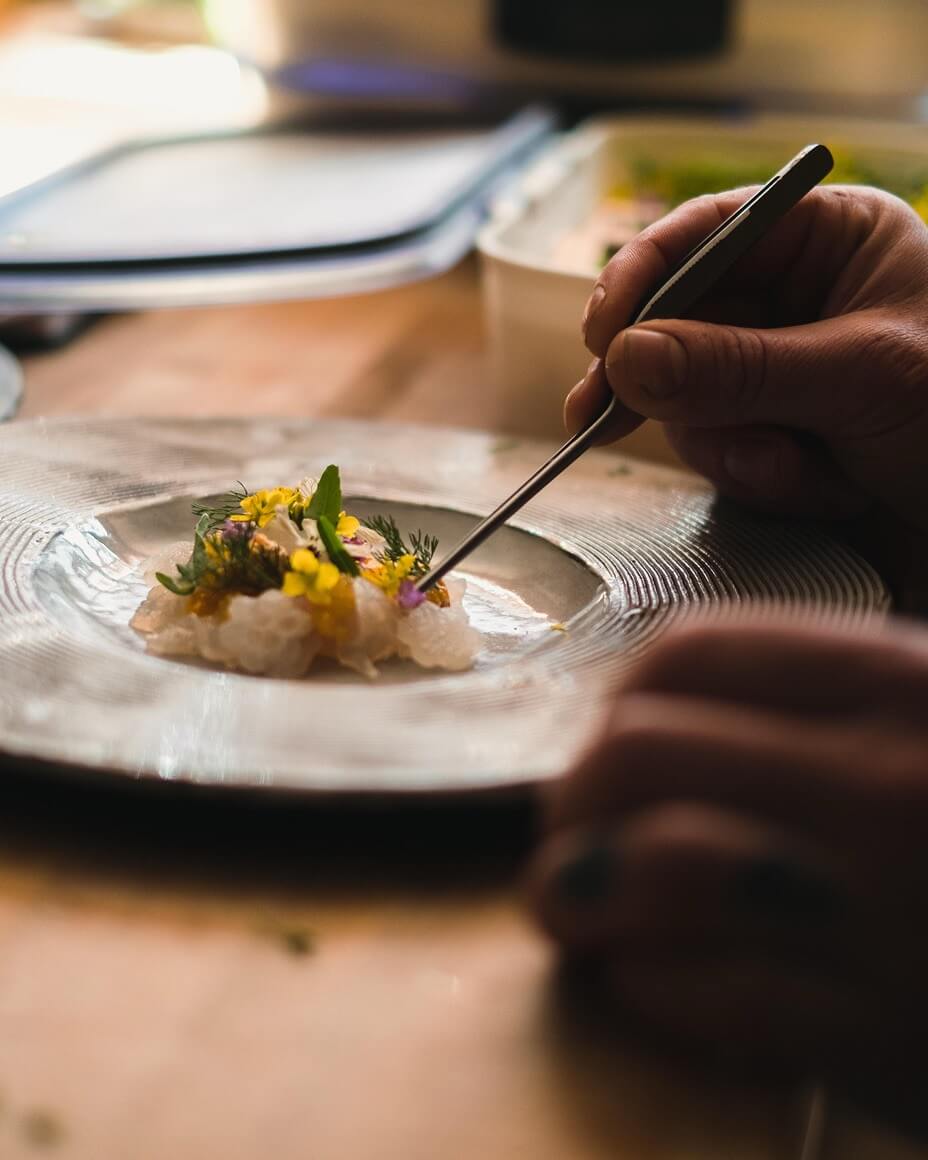 Edible flowers being plated on dish with tweezers