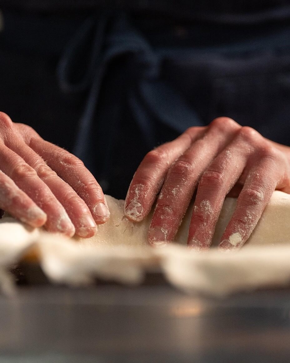 Hands pressing dough into pie dish