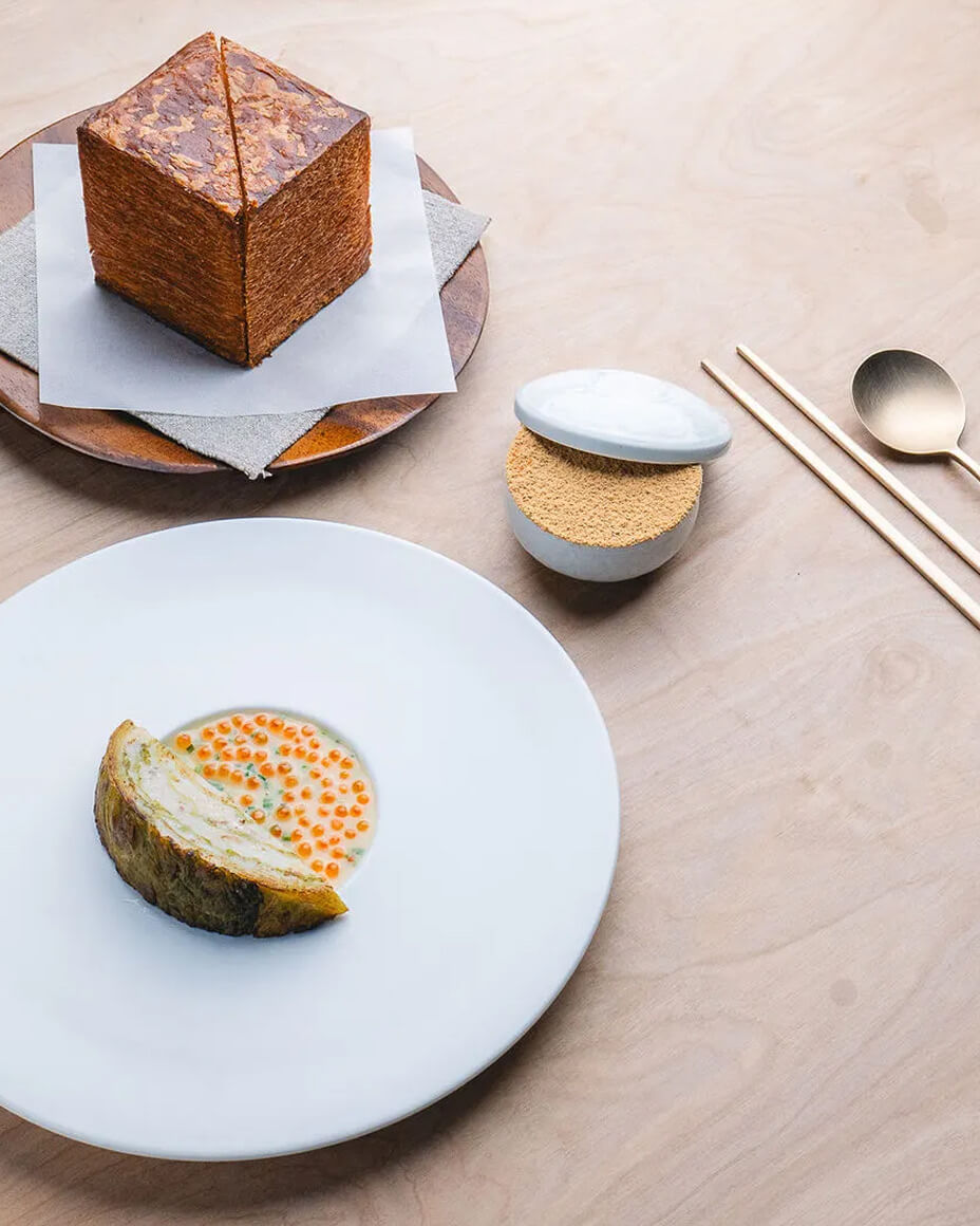 Table with simple and elegant plated dishes alongside artisan brass utensils