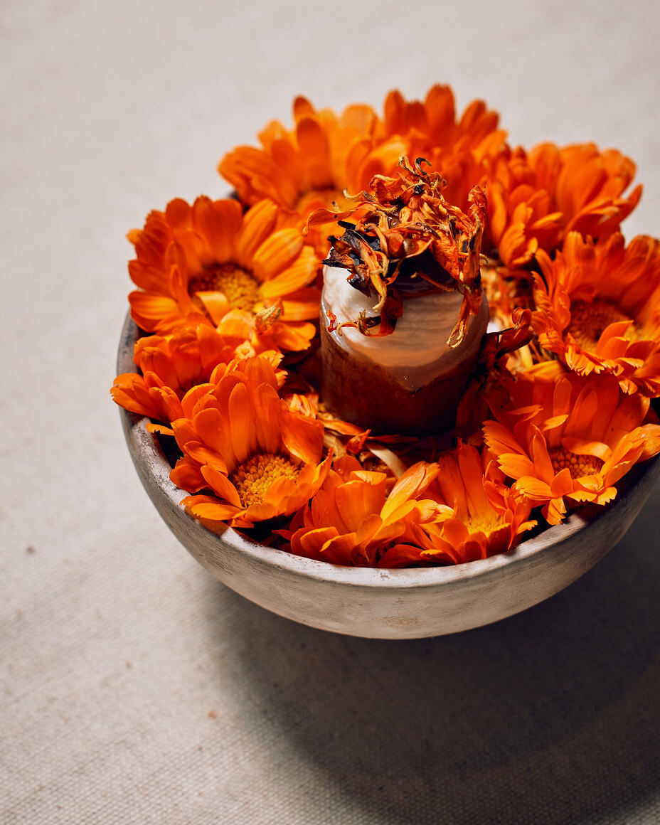 Bowl full of bright orange flowers with an edible element rising in the middle