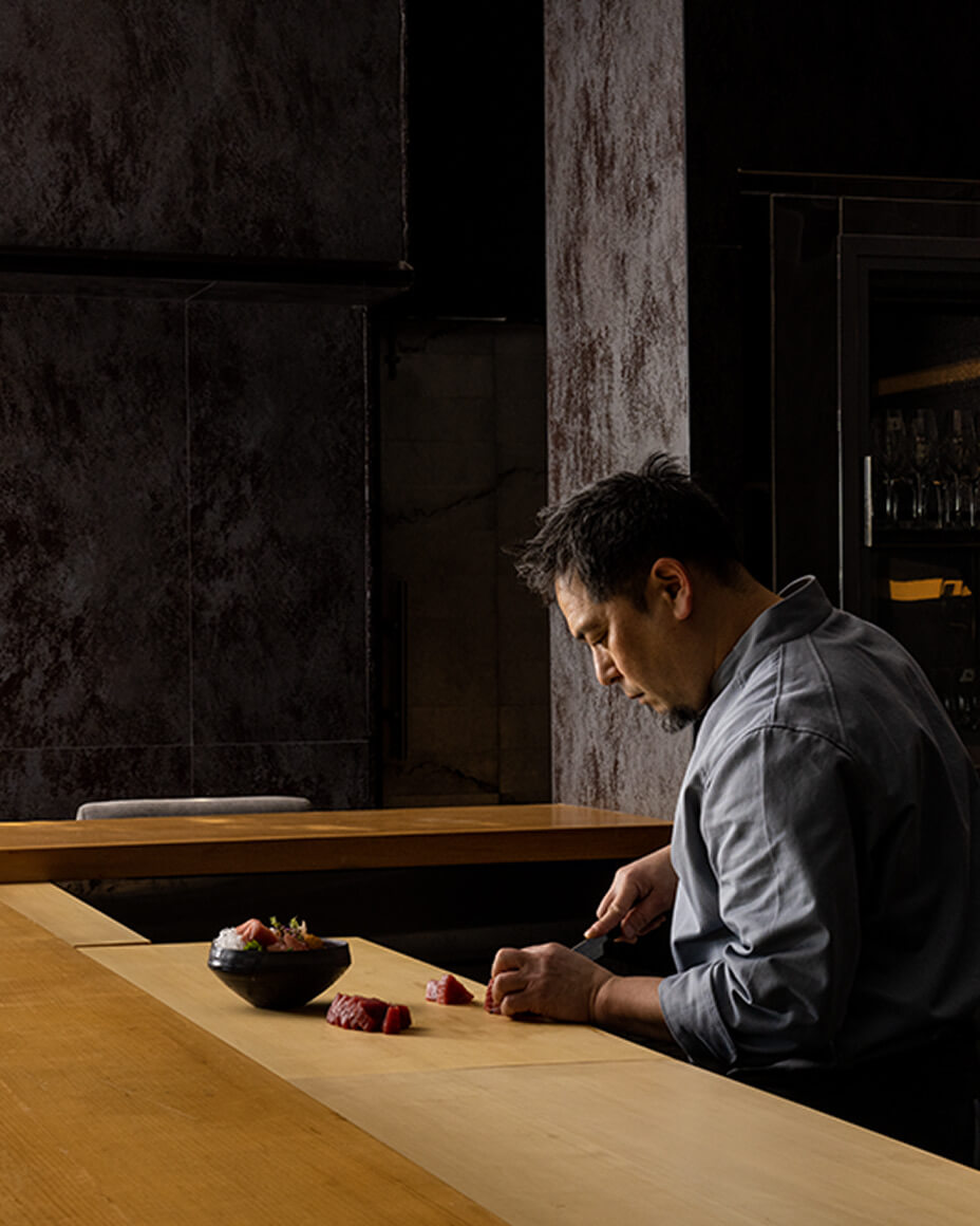 Chef Yoshitaka Mitsue slicing raw fish at the chef’s counter at UKA