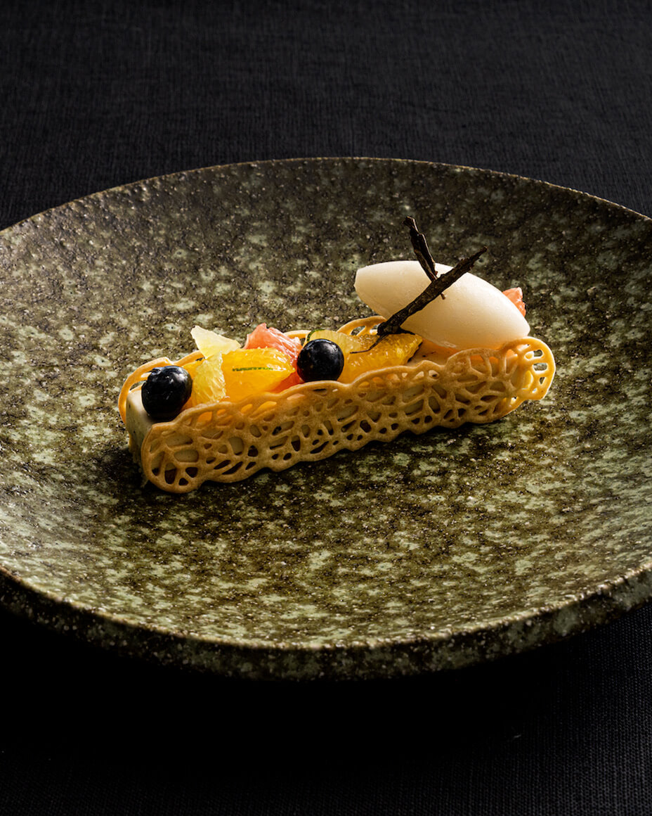Stone green plate with small elegantly plated dish with fresh fruit and a lace detail